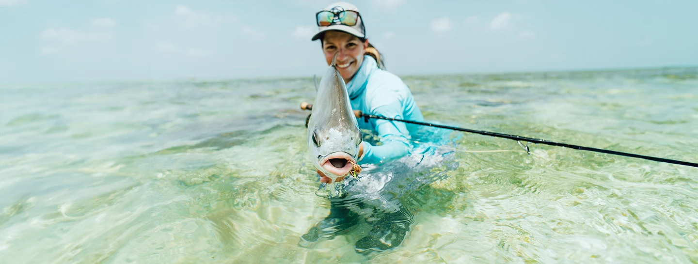 Watermark Belize Hotel fly fishing guest holds her catch in San Pedro Ambergris Caye